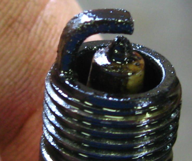 a wet and greasy black spark plug