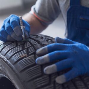 mechanic checking tire tread using a tire tread depth gauge