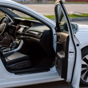 side shot of a white sedan with open an open passenger door