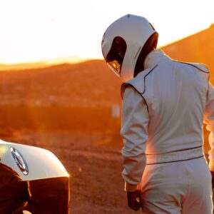 car racer with helmet standing beside a car