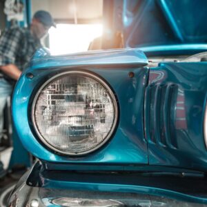 man fixing a classic blue car