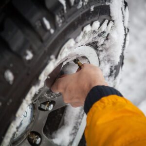 person checking tire pressure on a snowy day