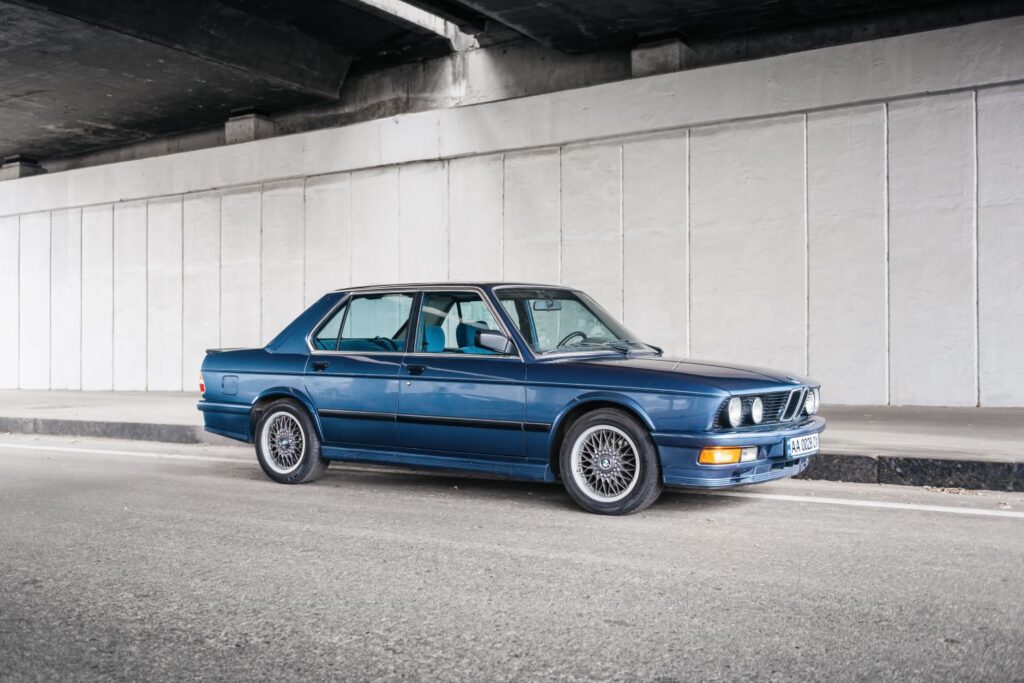 blue bmw 5 e28 parked under a bridge