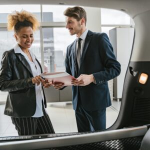 a man selling a car to a woman