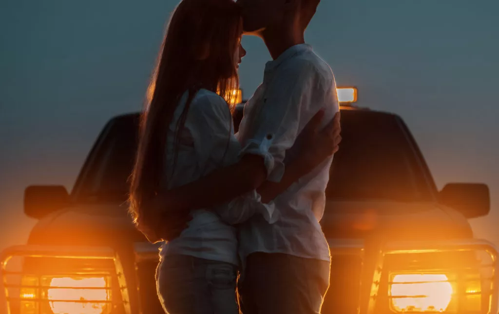 couple standing in front of headlights