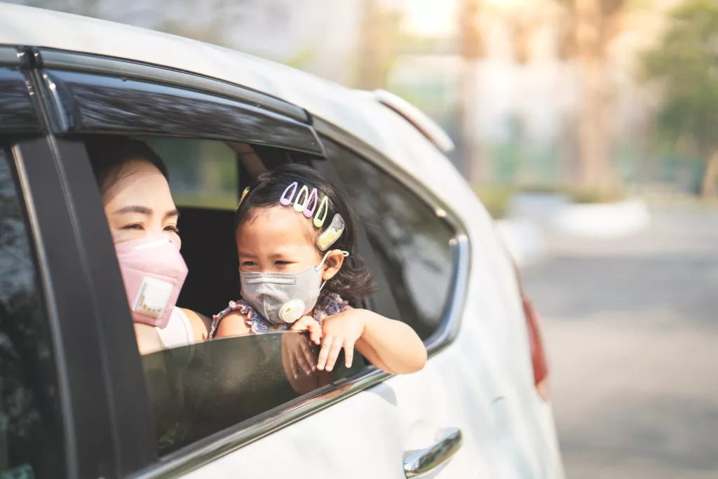 mother and daughter enjoying a road trip while wearing masks