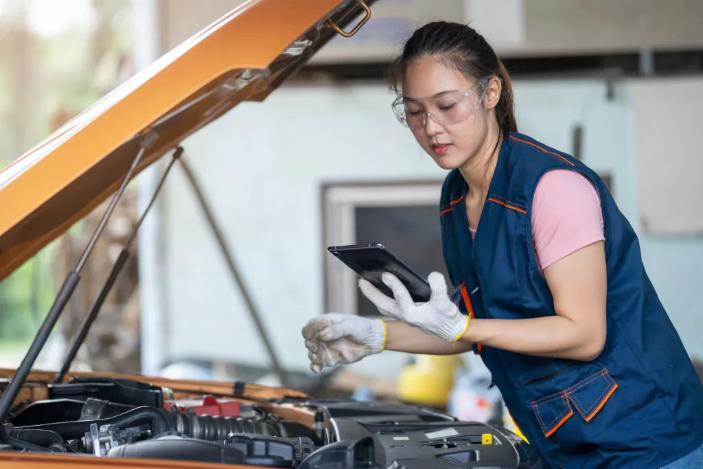 woman looking at online repair manual while fixing car