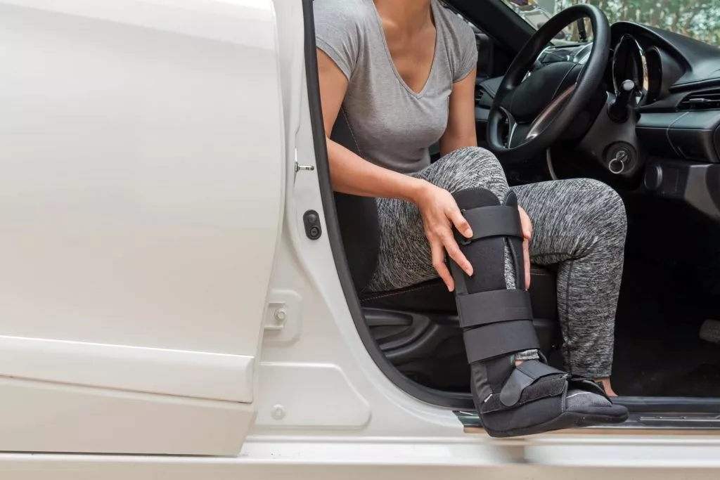 Injured woman wearing a black cast while sitting in the car