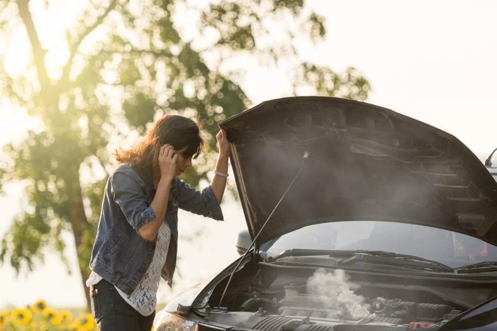 woman checking overheating car engine
