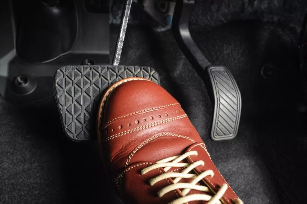 brown shoes lightly stepping on brake pedal