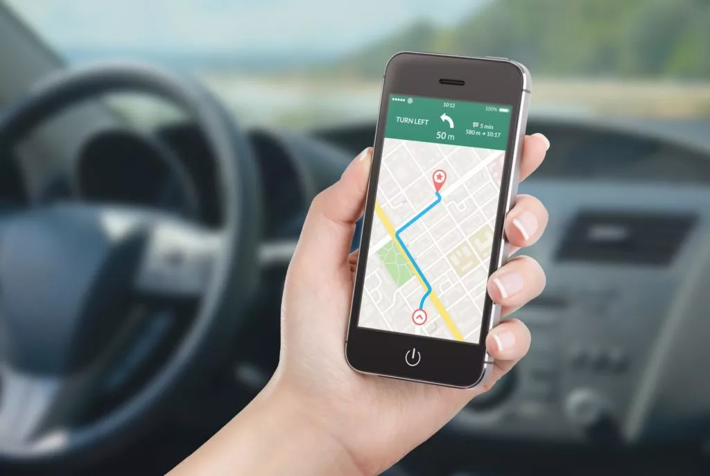 female driver holding phone with with map gps navigation application