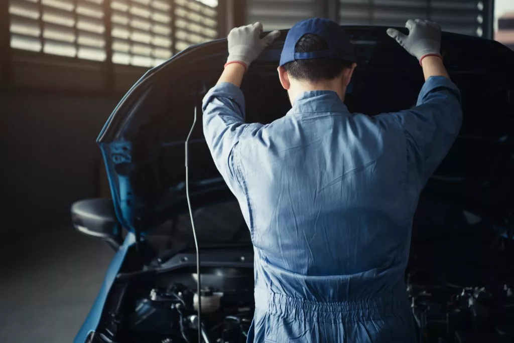 male mechanic looks through car hood to check ecm
