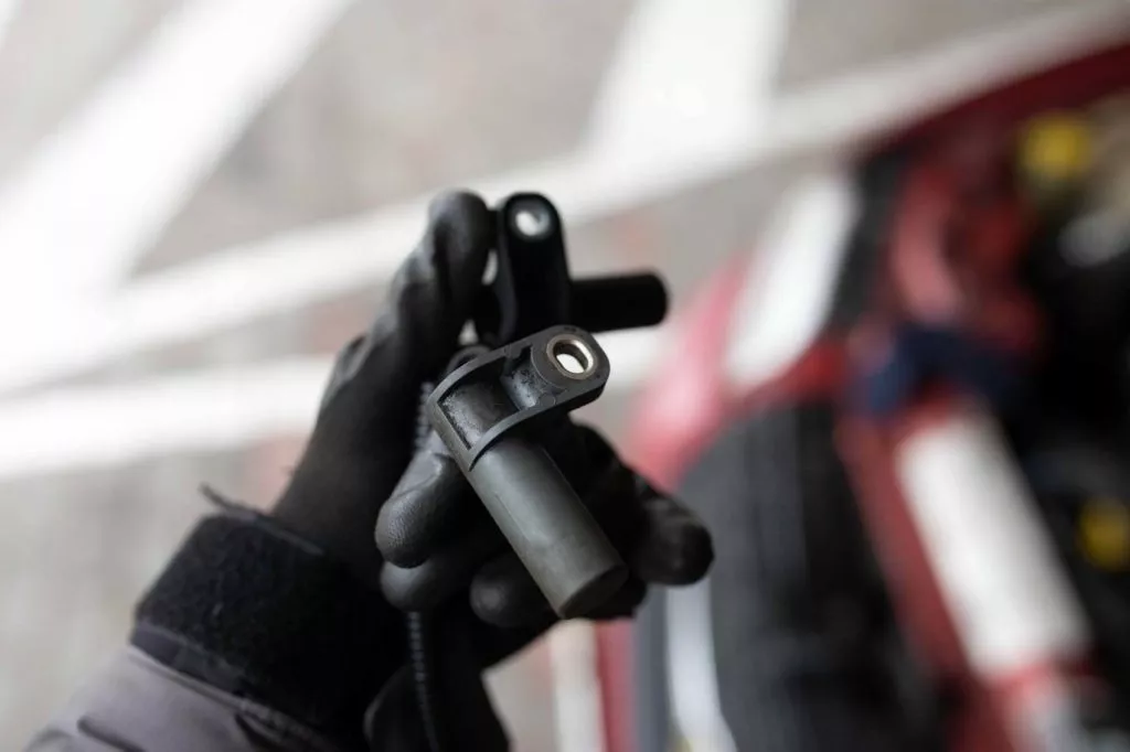 mechanic holding a new crankshaft position sensor