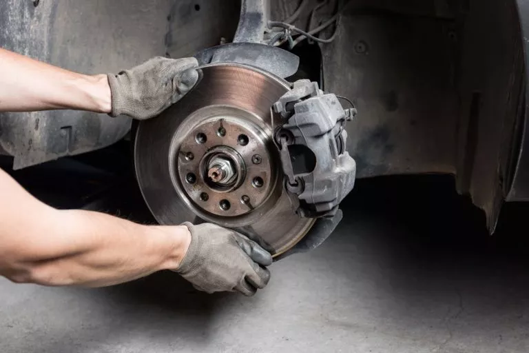 car mechanic hands replace brakes in garage