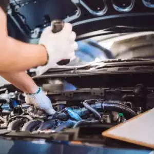 mechanic looks for a specific car part in the hood