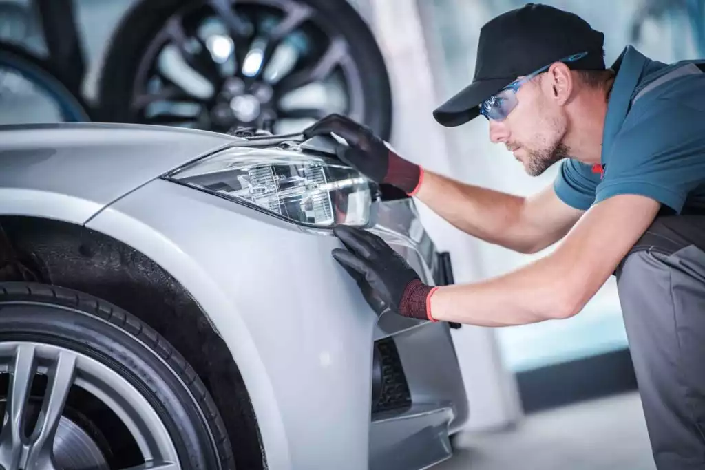 mechanic installing new headlight on a white car