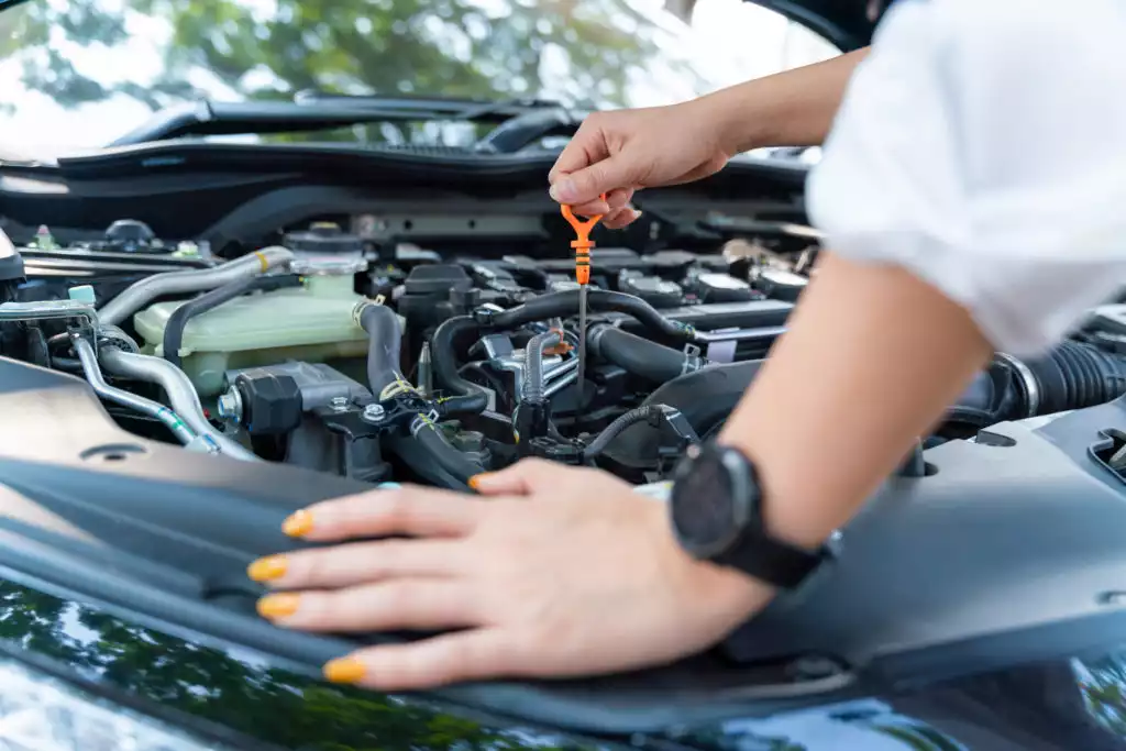 person checking engine oil level of car