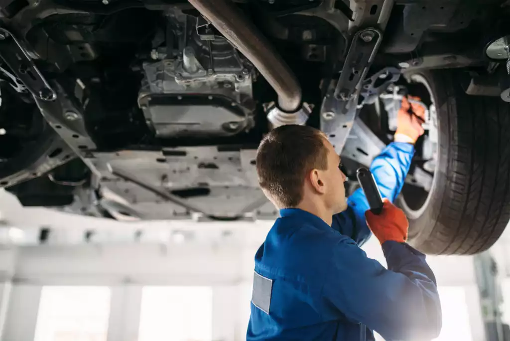 man inspects car brake hose and brake line