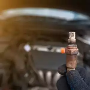 man holds a faulty old oxygen sensor with his hands