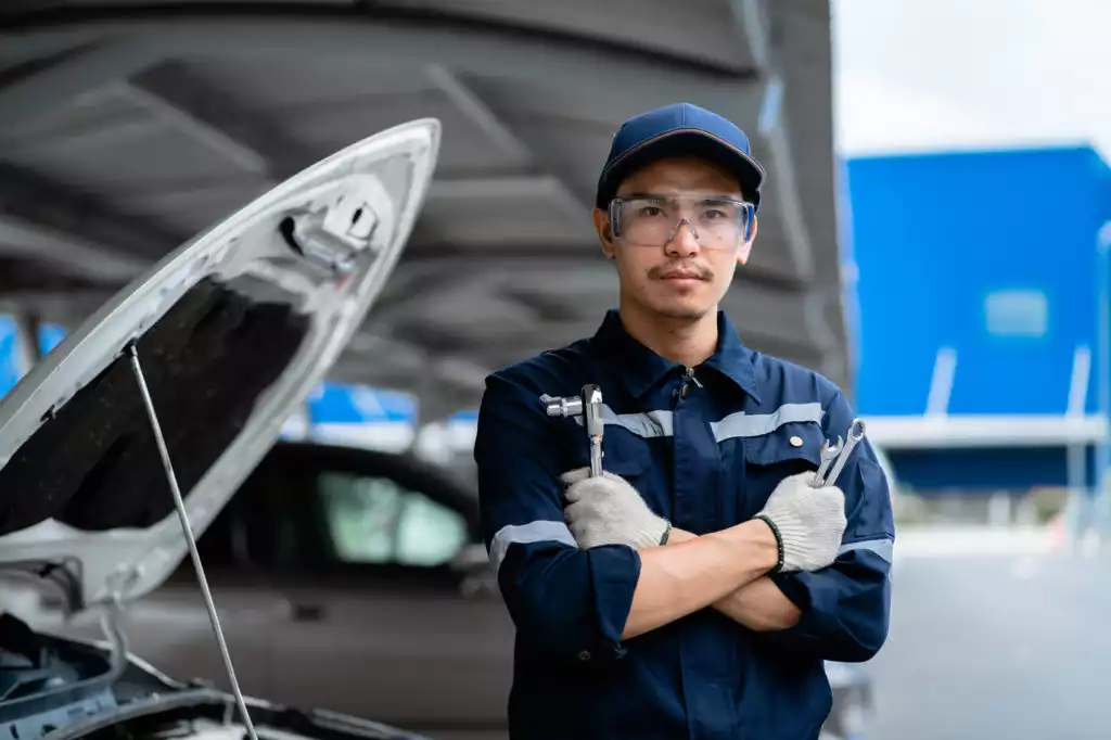 young asian mechanic checking the safety of a car