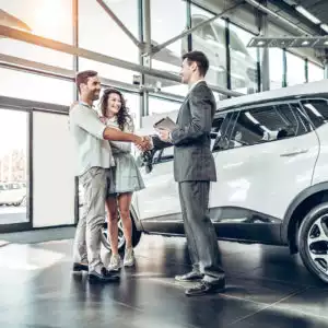 Couple shaking hands at car dealership