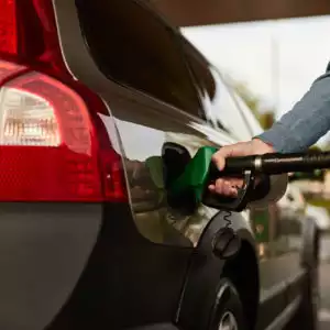 man holding fuel nozzle refueling car
