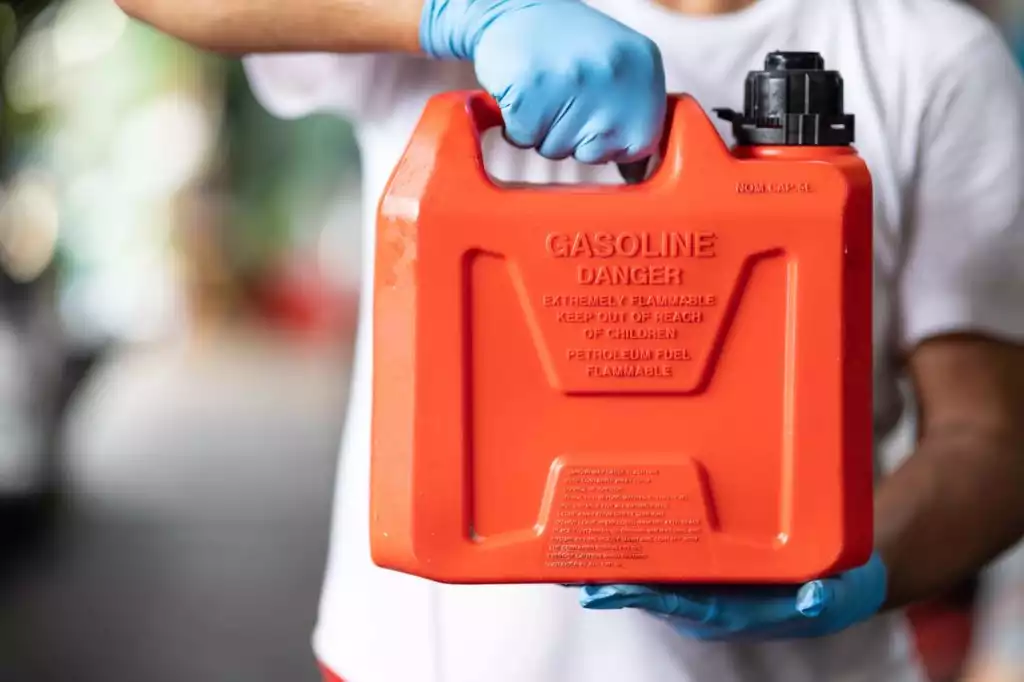 male holding red plastic fuel gallon