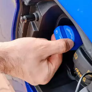 man removing cap to pour diesel exhaust fluid