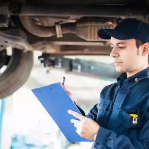 mechanic takes note while under car