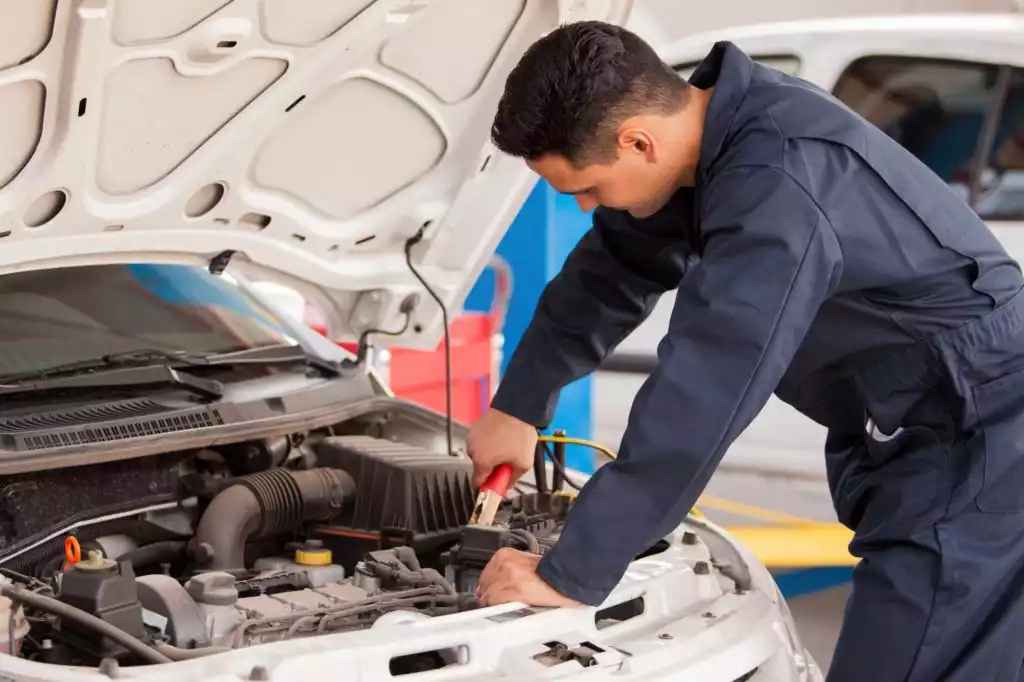 male mechanic jump starts a car battery
