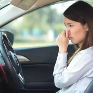 female driver covering nose because of burning oil smell