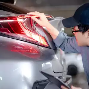 asian mechanic checks car brake lights