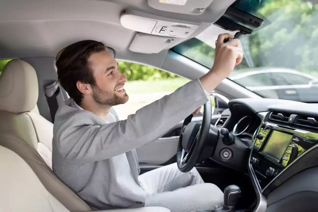 driver adjusting auto dimming rearview mirror