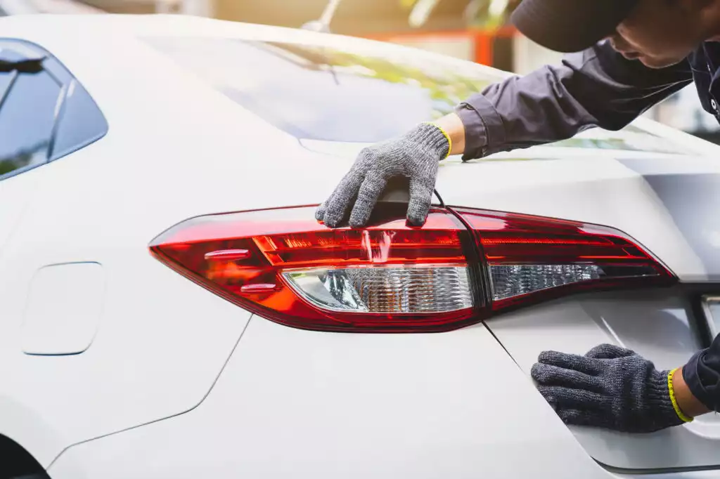 mechanic checking brake lights of a white car