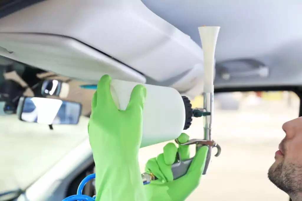spraying upholstery cleaner to a car headliner