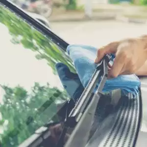 person cleaning windshield wipers with a cloth