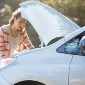 woman checking the engine of a white car