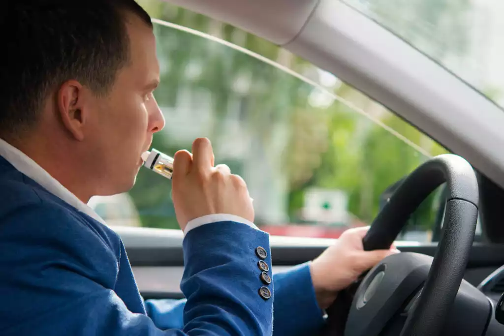 man holding electric cigerette inside car
