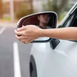 driver's hand adjusting side mirror