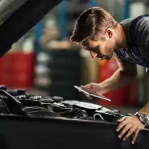 Young,Auto,Mechanic,With,Touchpad,Examining,Car,Engine,In,Repair