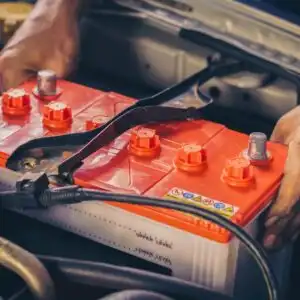 hands lifting a car battery