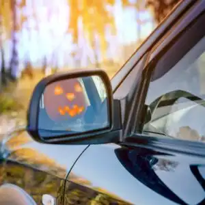 jack-o-lantern reflection in a car mirror