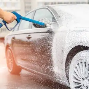 man using a foam cannon to a car