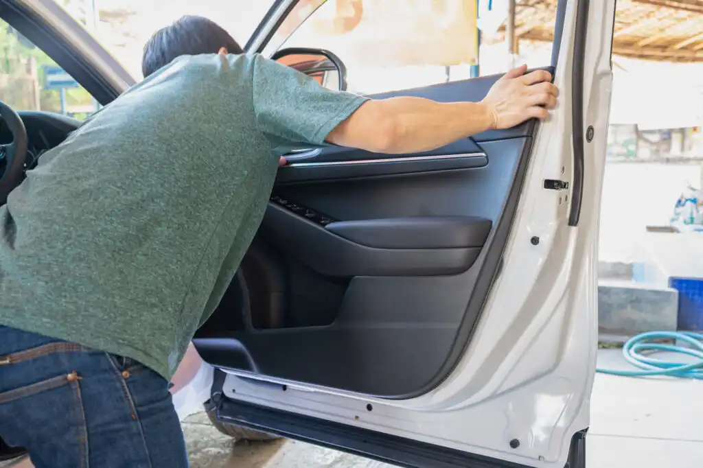 man fixing sagging car door panel