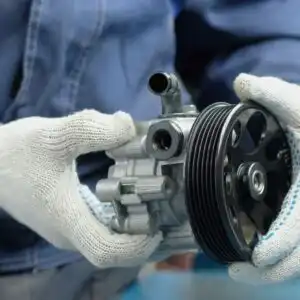 mechanic holding a power steering pump