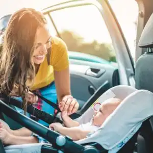 mother putting a baby in a car seat