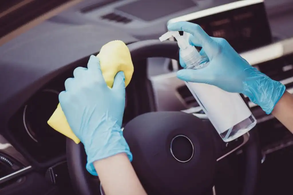 glove hands sanitizing the steering wheel