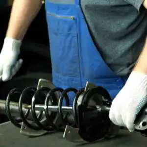 mechanic holding a replacement shock absorber