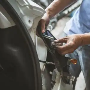 man replacing a car's tail light bulb
