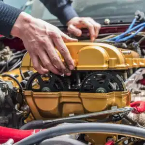 person putting a yellow engine cover to a car engine